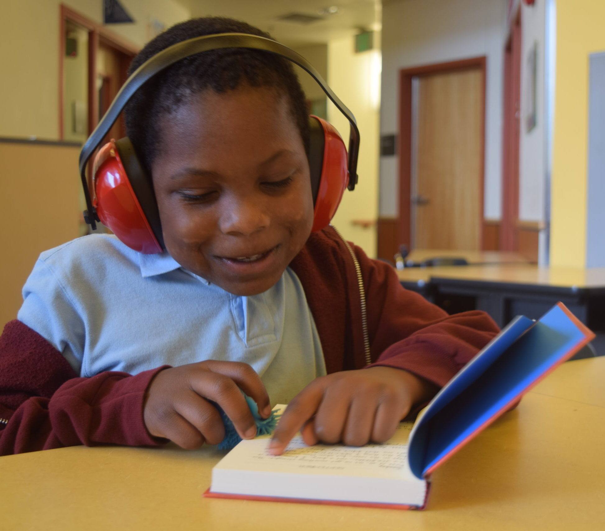 a student wearing sensory headphones and reading a novel