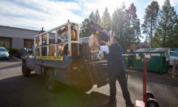 two men load a Les Schwab truck with packages for teachers