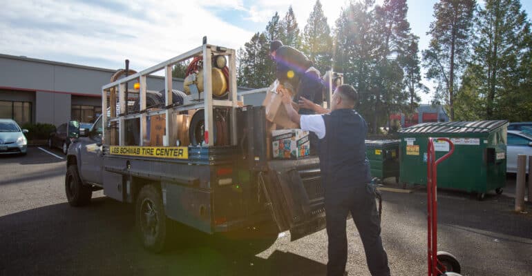 two men load a Les Schwab truck with packages for teachers